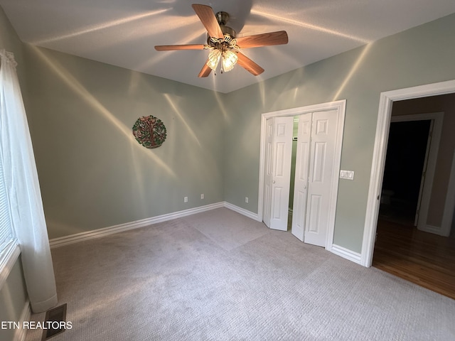 unfurnished bedroom with carpet, a closet, ceiling fan, and baseboards