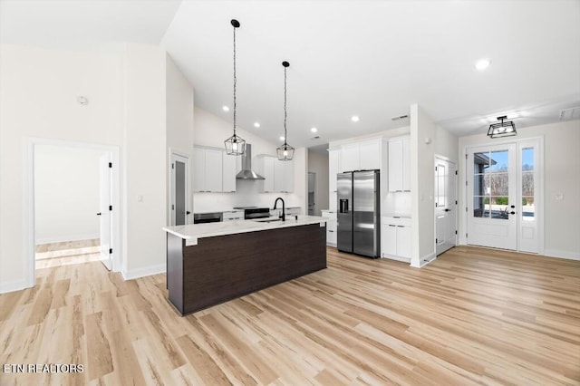 kitchen featuring white cabinets, wall chimney exhaust hood, stainless steel refrigerator with ice dispenser, and hanging light fixtures