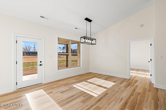 unfurnished dining area with light hardwood / wood-style floors and an inviting chandelier