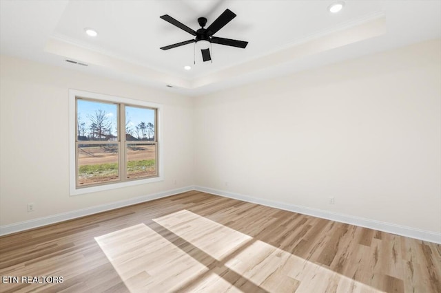 spare room featuring ceiling fan, light hardwood / wood-style floors, and a tray ceiling