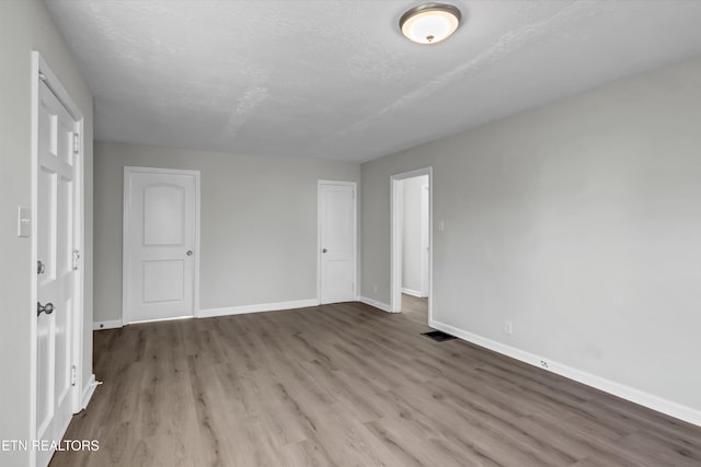 unfurnished room featuring hardwood / wood-style flooring and a textured ceiling