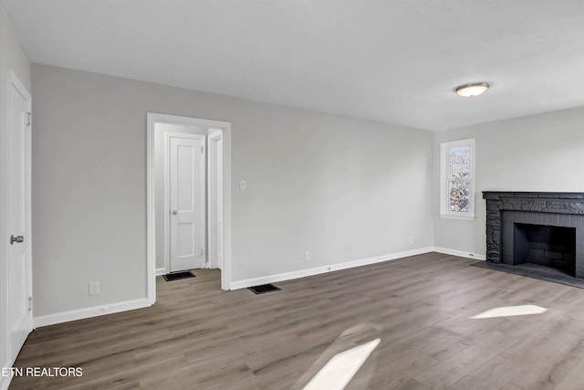 unfurnished living room with a brick fireplace and hardwood / wood-style floors