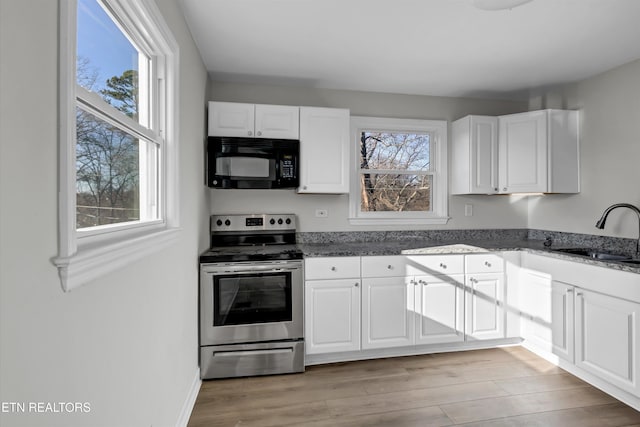 kitchen featuring dark stone countertops, sink, white cabinets, and stainless steel range with electric cooktop