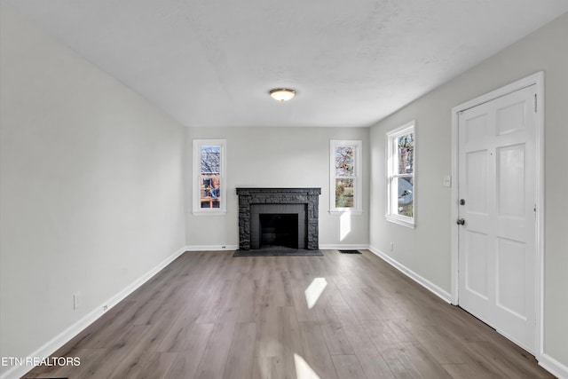 unfurnished living room featuring wood-type flooring and a brick fireplace