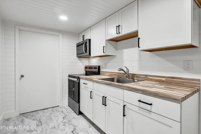 kitchen with white cabinetry, sink, butcher block countertops, and black range with electric cooktop