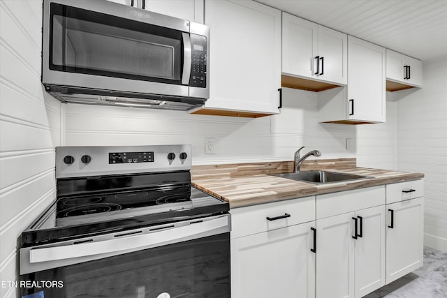 kitchen featuring wooden counters, appliances with stainless steel finishes, sink, and white cabinetry