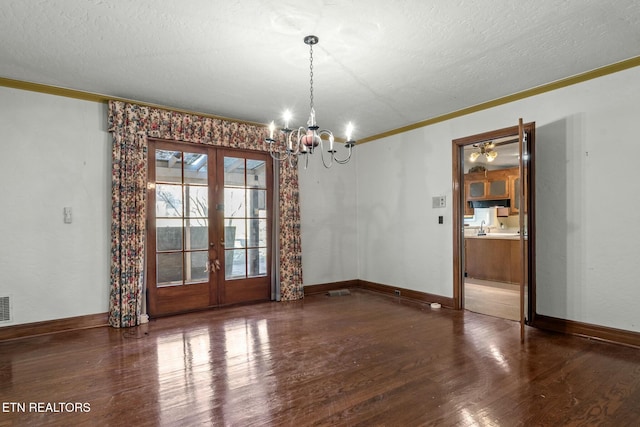 unfurnished room featuring crown molding, dark wood-type flooring, french doors, and a chandelier