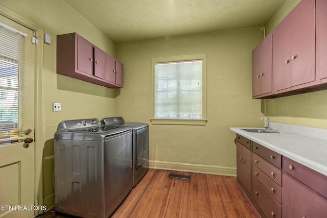 laundry area featuring cabinets, sink, hardwood / wood-style floors, and washing machine and clothes dryer