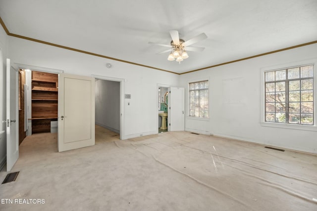 unfurnished bedroom featuring a spacious closet, light colored carpet, ornamental molding, a closet, and ceiling fan