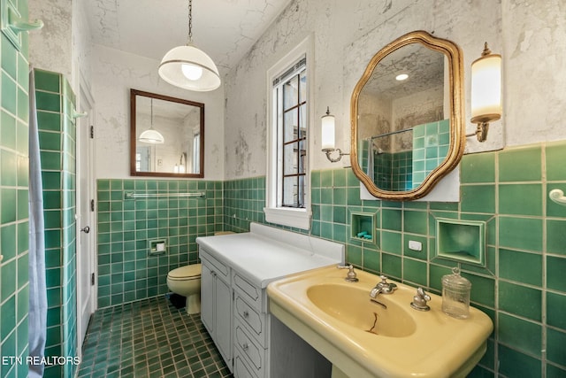 bathroom featuring tile patterned floors, a healthy amount of sunlight, sink, and tile walls