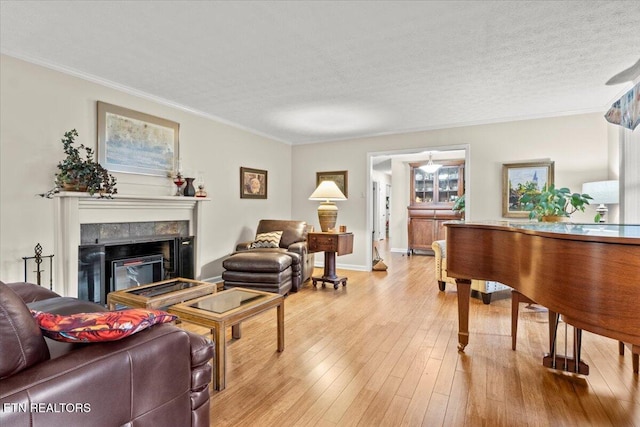 living room featuring a textured ceiling, ornamental molding, and light wood-type flooring