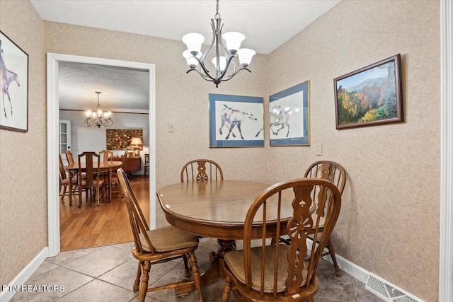 dining area with tile patterned floors, ornamental molding, and a notable chandelier