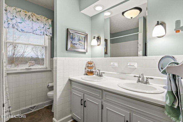 bathroom featuring toilet, tile walls, tile patterned floors, a textured ceiling, and vanity