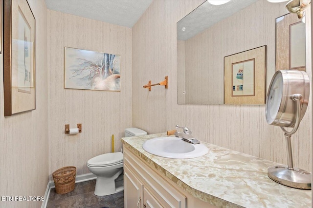 bathroom featuring toilet, a textured ceiling, and vanity