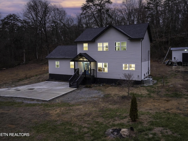 view of front of house with a patio area, central AC, and roof with shingles