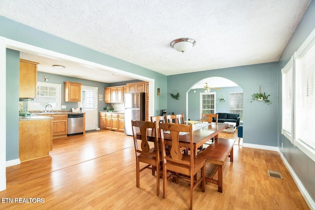 dining area featuring ceiling fan, light hardwood / wood-style flooring, a textured ceiling, and sink