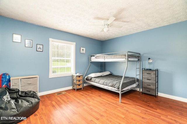 bedroom featuring ceiling fan, wood-type flooring, and a textured ceiling