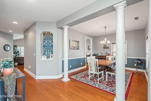 dining room featuring ornate columns, hardwood / wood-style flooring, plenty of natural light, and a notable chandelier