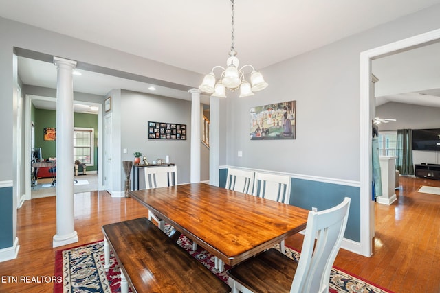 dining room featuring hardwood / wood-style flooring, a notable chandelier, and decorative columns