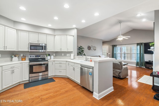 kitchen featuring kitchen peninsula, appliances with stainless steel finishes, ceiling fan, sink, and white cabinetry