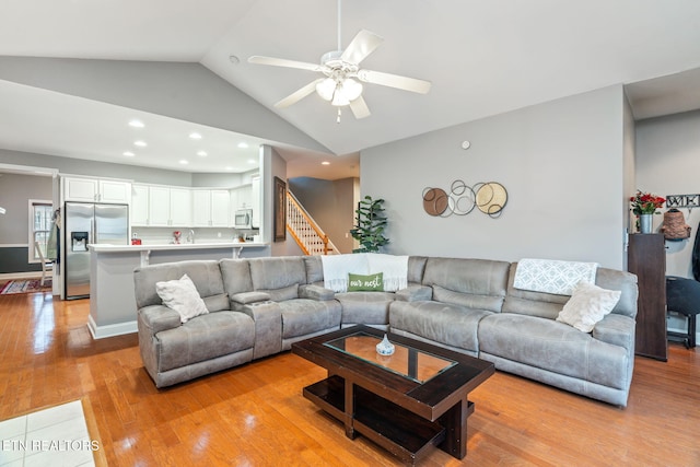 living room with light hardwood / wood-style flooring, vaulted ceiling, and ceiling fan