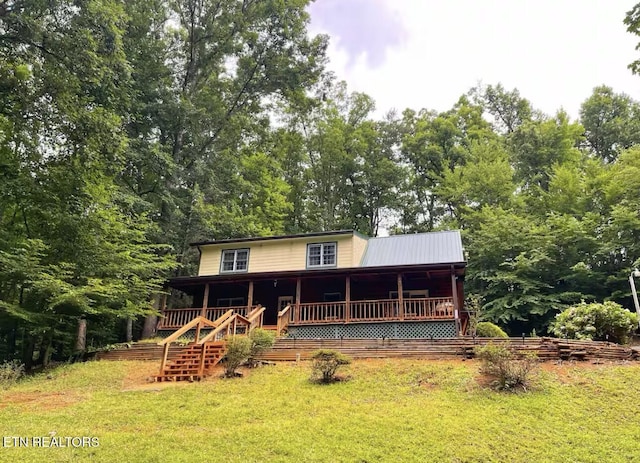 rear view of property with covered porch and a yard