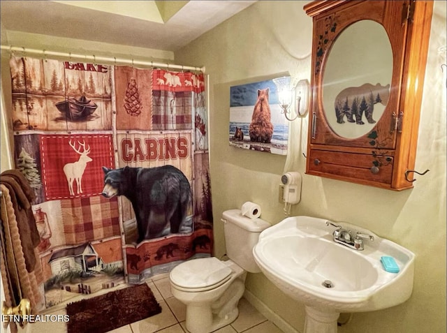 bathroom featuring curtained shower, sink, tile patterned flooring, and toilet