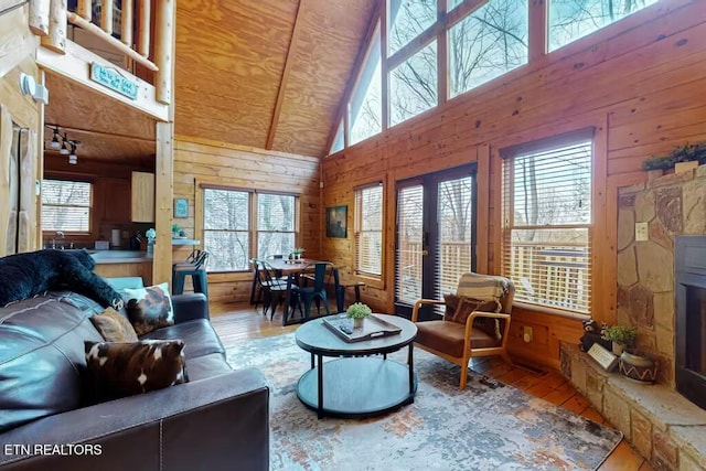 living room featuring wooden walls, high vaulted ceiling, and wood-type flooring