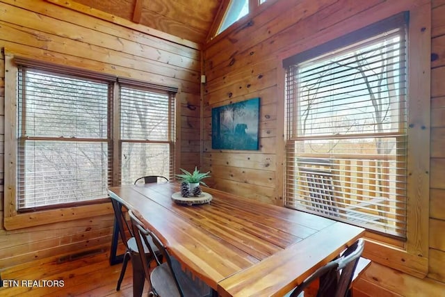 dining space with wooden walls and vaulted ceiling