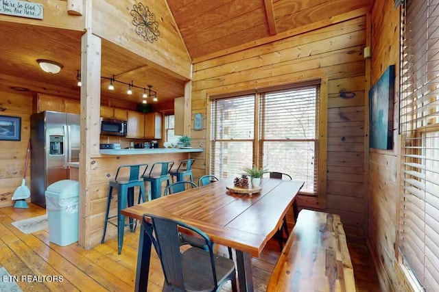 dining room featuring wooden ceiling, wood walls, lofted ceiling, and light hardwood / wood-style flooring