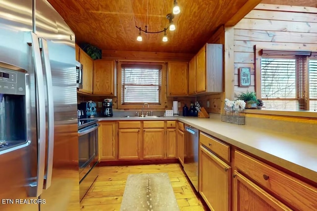 kitchen featuring wood walls, sink, light wood-type flooring, appliances with stainless steel finishes, and wood ceiling