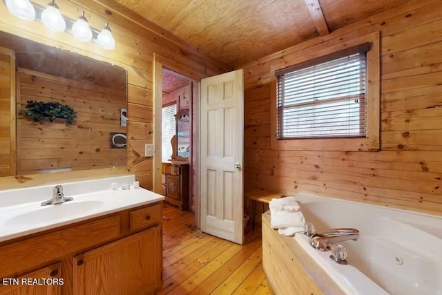 bathroom featuring a bath, wood-type flooring, wooden walls, vanity, and wood ceiling