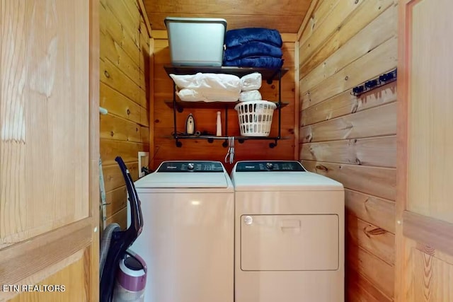 washroom featuring wood walls and washing machine and clothes dryer