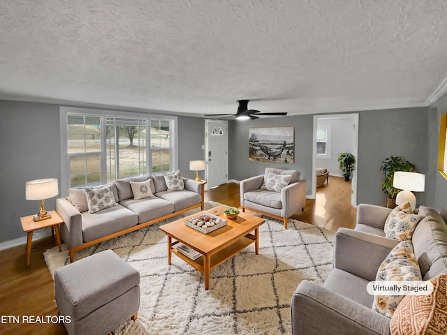 living room featuring hardwood / wood-style floors, ceiling fan, and a textured ceiling