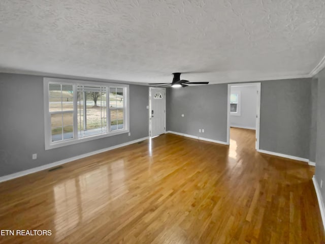 unfurnished living room with hardwood / wood-style floors, ceiling fan, and a textured ceiling