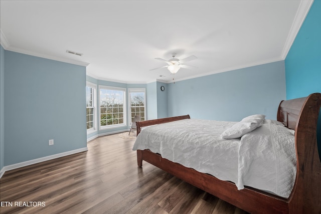 bedroom with visible vents, crown molding, baseboards, and wood finished floors