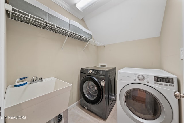 laundry area featuring light tile patterned flooring, laundry area, independent washer and dryer, and a sink