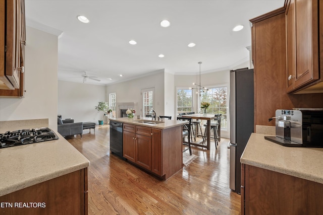 kitchen with open floor plan, light wood-style floors, black appliances, a ceiling fan, and a sink