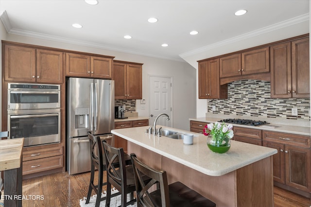 kitchen with a sink, appliances with stainless steel finishes, dark wood finished floors, and crown molding