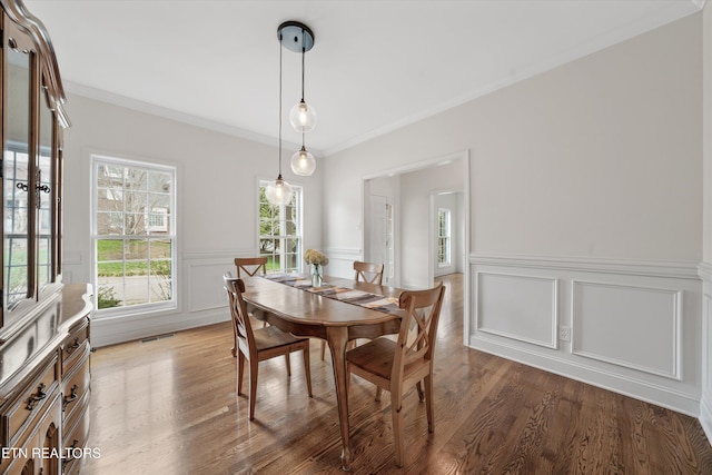 dining space with visible vents, a wainscoted wall, wood finished floors, and crown molding