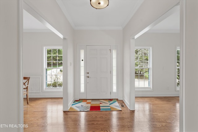 entrance foyer with visible vents, baseboards, wood finished floors, and ornamental molding