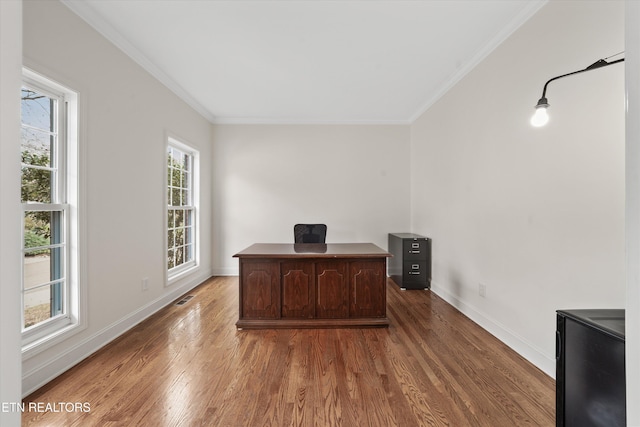 unfurnished office with visible vents, ornamental molding, baseboards, and wood finished floors