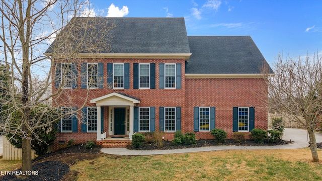 view of front of property featuring brick siding, roof with shingles, and a front lawn