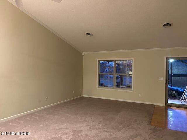 carpeted spare room with vaulted ceiling and crown molding