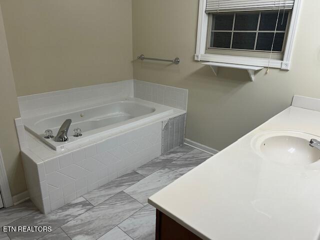 bathroom featuring vanity and tiled bath