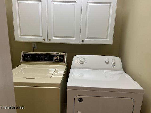 clothes washing area with washer and dryer and cabinets