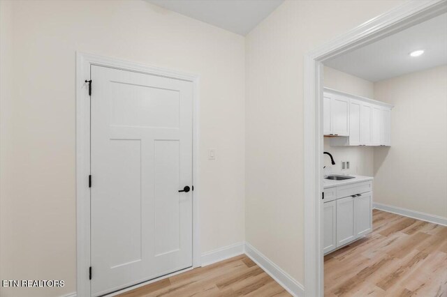 corridor featuring light wood-type flooring and sink