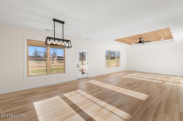 unfurnished living room with a raised ceiling, a healthy amount of sunlight, and light hardwood / wood-style floors