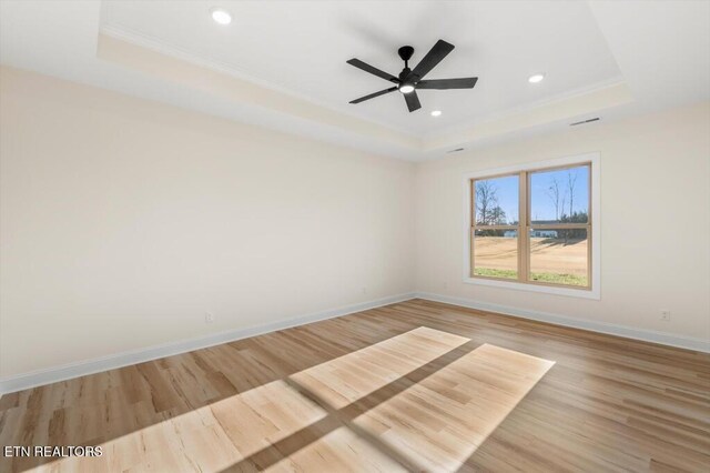 empty room featuring light hardwood / wood-style floors, a raised ceiling, ceiling fan, and ornamental molding