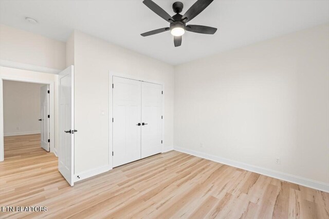 unfurnished bedroom with ceiling fan, a closet, and light wood-type flooring